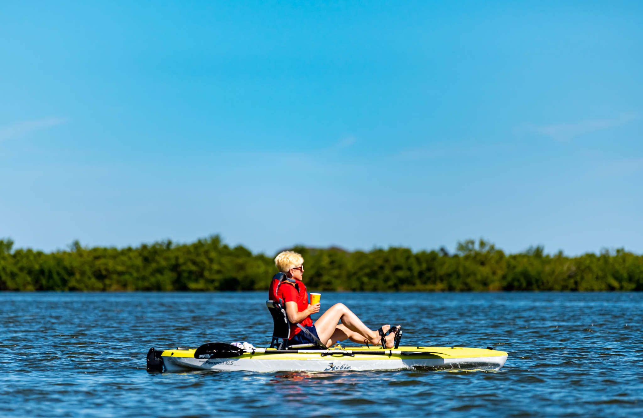 Woman drinking coffee in Viking EcoTours pedal kayak on the Sunrise and Morning kayak tour through Canaveral National Seashore. This tour area is a National Park near Orlando, New Smyrna Beach, and Daytona Beach.
